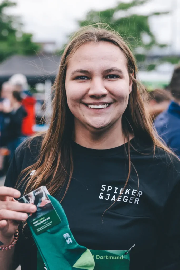 Lächelnde Person mit grünen Socken in der Hand