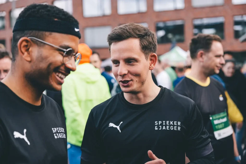 Zwei Männer im Gespräch, Sportbekleidung tragend.