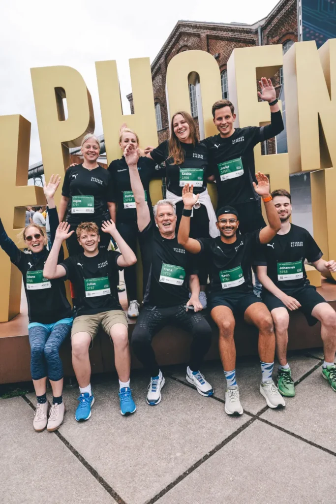 Läuferteam posiert vor großem Schriftzug.