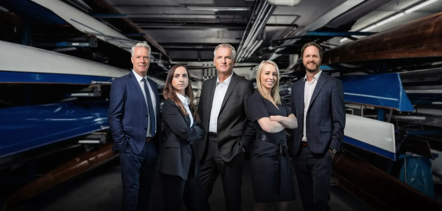 Fünf Personen in Anzügen mit Booten im Hintergrund