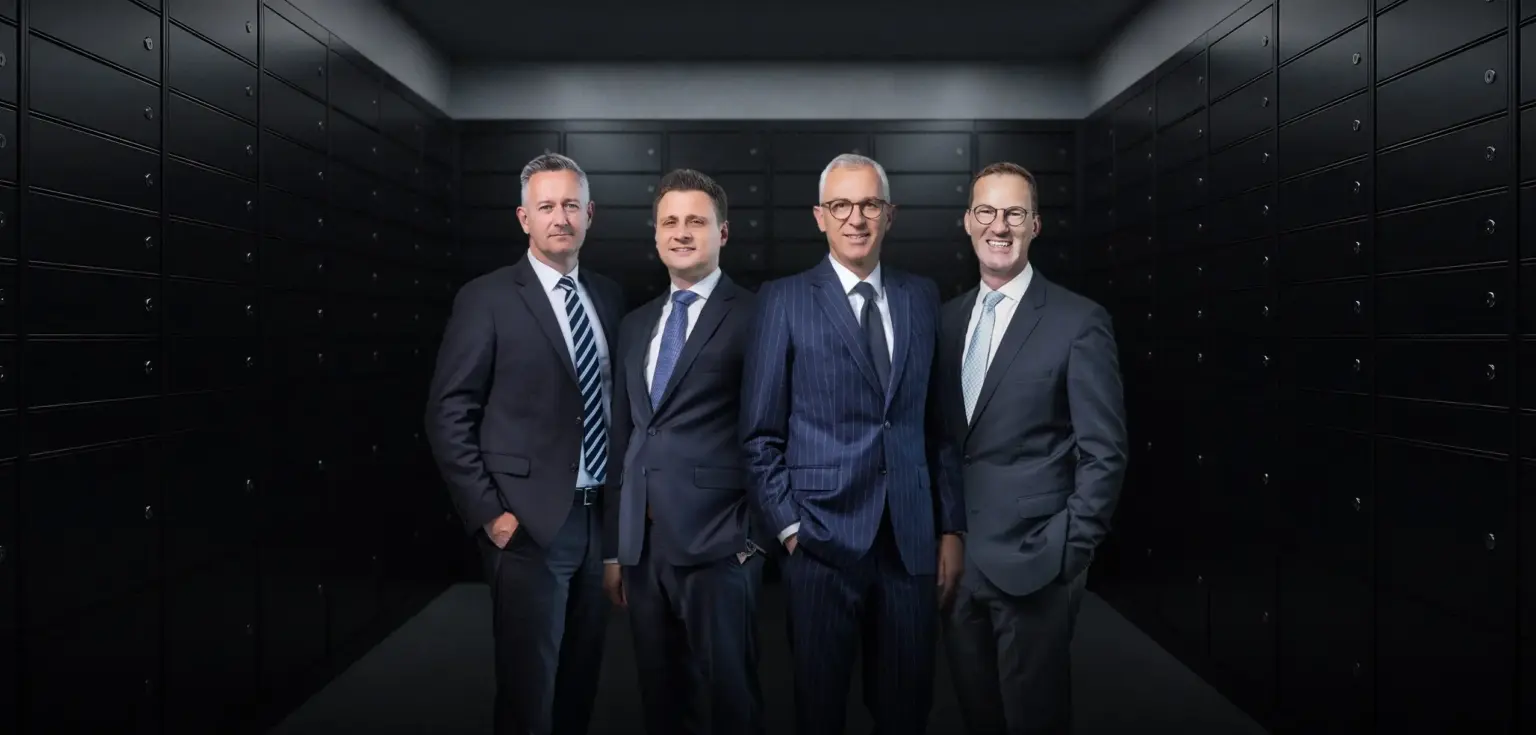 Vier Männer in Anzügen vor Schließfächern