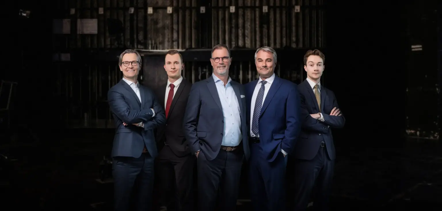 Fünf Männer in Anzügen vor schwarzem Hintergrund