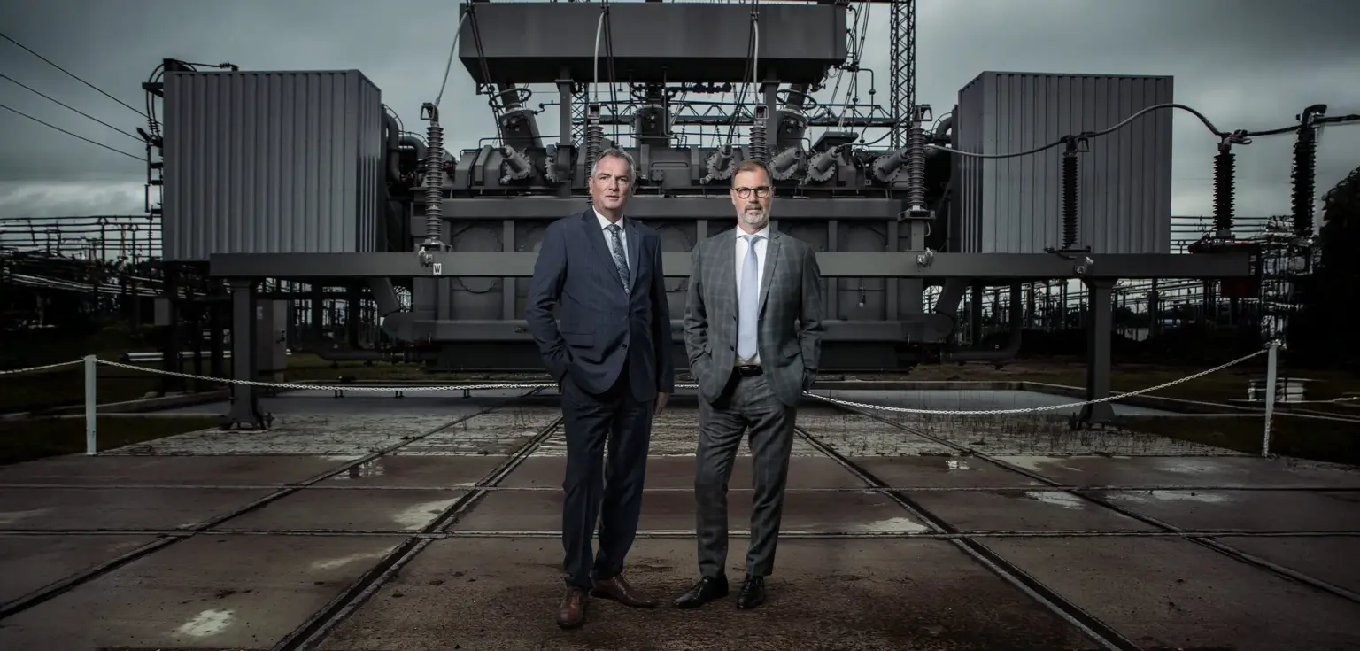 Zwei Männer vor einem Transformator auf einem Gelände