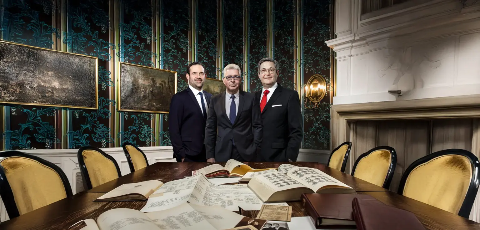 Drei Männer in einem eleganten Raum mit Büchern