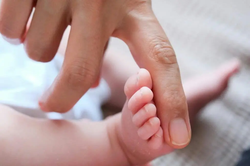 Hand berührt den kleinen Fuß eines Babys