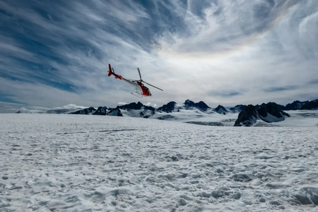 Helicopter flying over snowy mountain glacier landscape