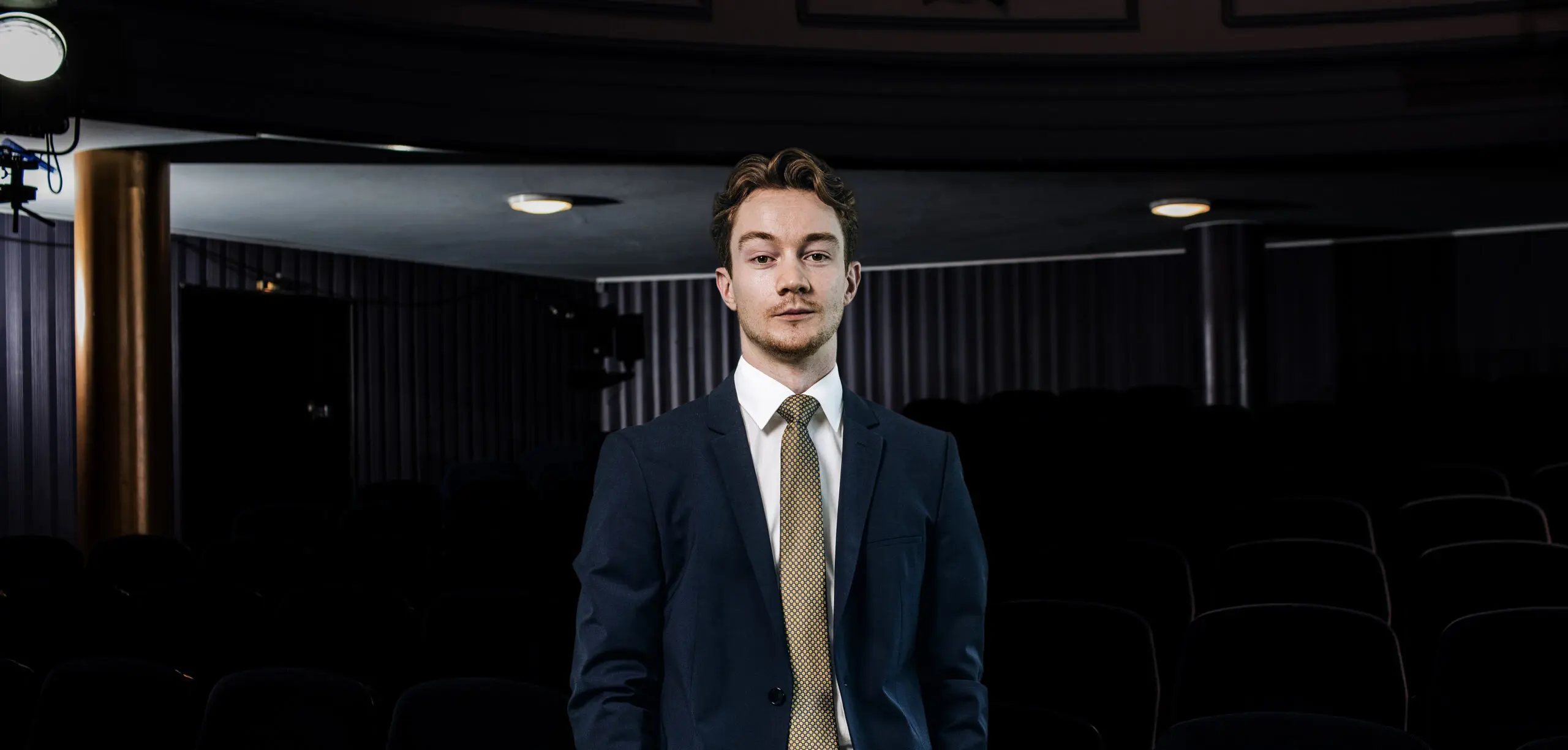 Mann in Anzug steht im Theater.