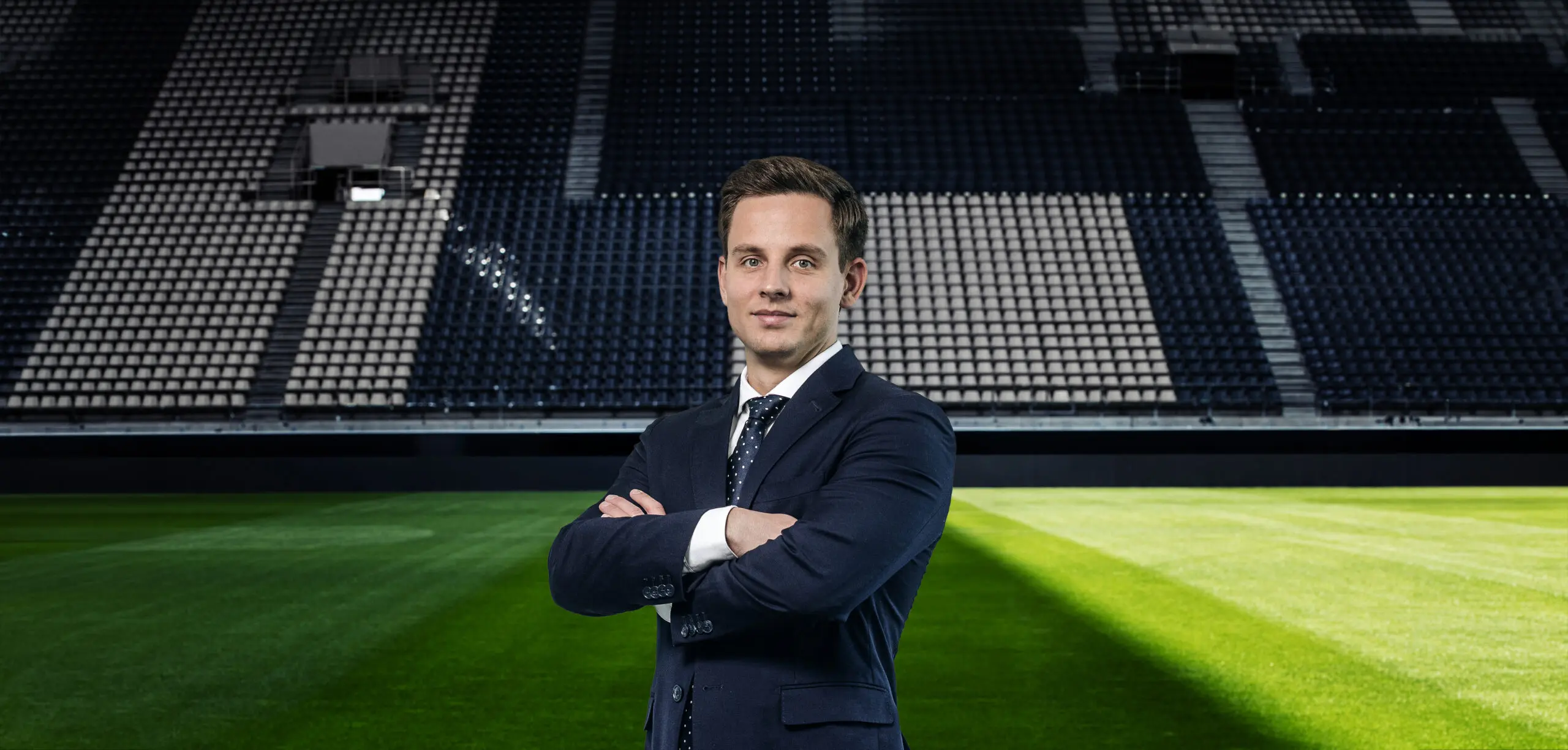 Mann im Anzug auf einem Fußballfeld.