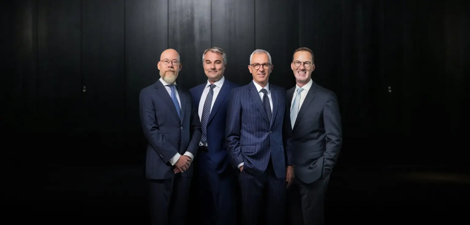 Vier Männer in Anzügen stehen zusammen.