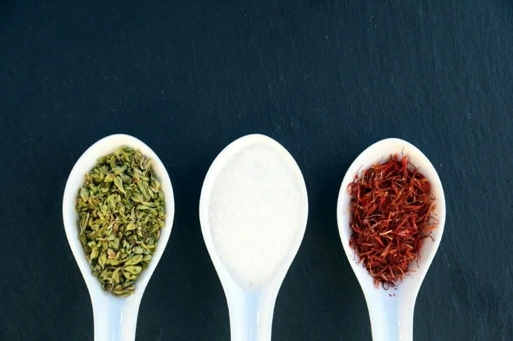 Three spoons with different spices and sugar.