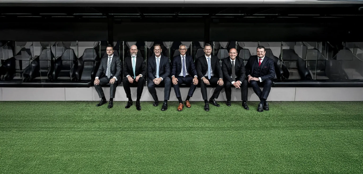 Sieben Männer auf einer Bank in Anzügen